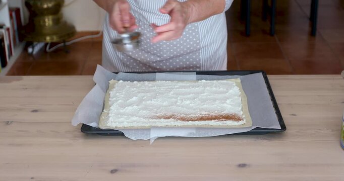 Dusting Ricotta Pastry Filling with Cinnamon Through Small Sieve. Unrecognizable people.