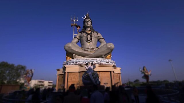 Massive statue of Lord Shiva with trishul at Char Dham Temple in Vrindavan, India, set against a clear blue sky. This iconic spiritual landmark represents meditation.