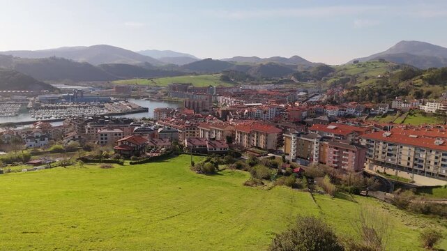 Aerial view of Zumaia harbor town beyond a vegetated cliff