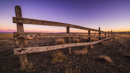 Obraz premium Scenery featuring a dilapidated wooden fence in arid grassland.