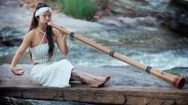 Captivating Melodies: A Musician Plays a Traditional Instrument didgeridoo by the Riverbank, Merging Nature's Harmony with Cultural Expression in a Serene Outdoor Setting