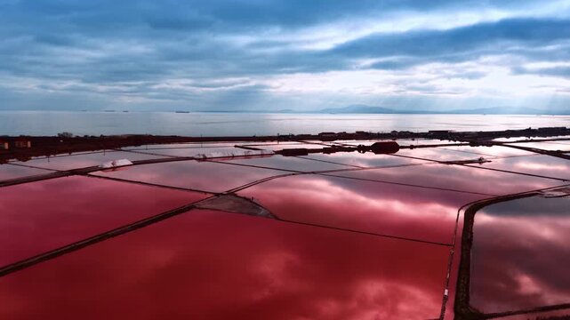Moving slowly over the pink salty lakes reflecting cloudy sky. Seascape in the backdrop.