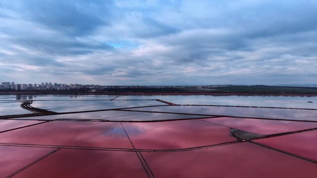 Large pink salty lakes against cloudy sky. Salt production industry. Aerial view.
