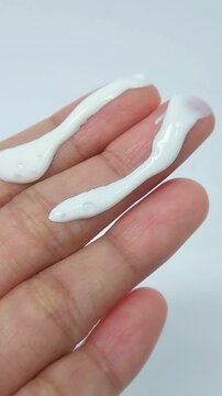 Showing white cream on two fingers. Close up view, skincare product concept, beauty treatment presentation