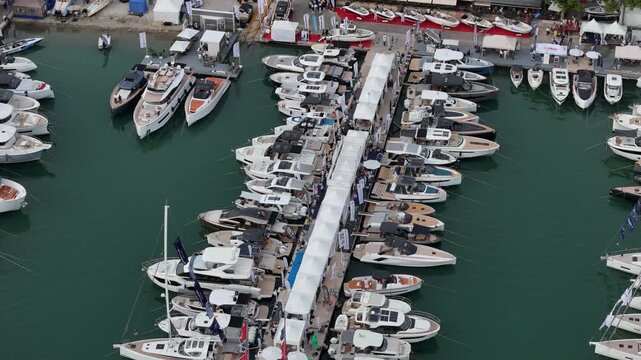 Aerial view of luxury yachts docked at marina during international boat show in Palma de Mallorca, Balearic Islands, Spain. Crowded harbor with modern vessels, sailing boats, and visitors exploring ex