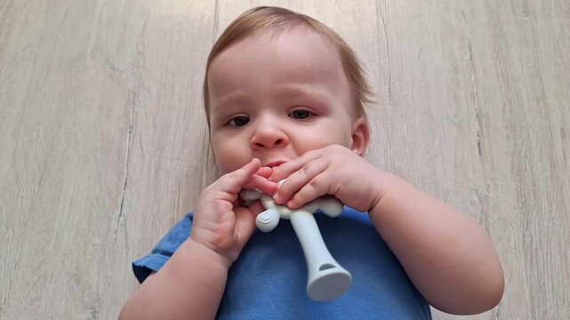Cute caucasian baby boy lying on floor and teething