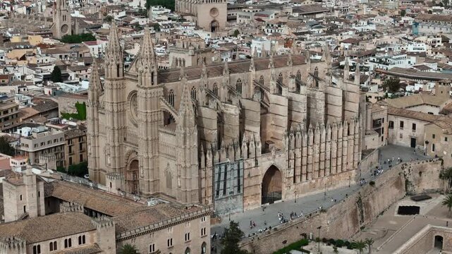 Aerial drone view of Palma Cathedral (La Seu) dominating historic old town skyline in Palma de Mallorca, Spain. Gothic architecture, coastal cityscape, Mediterranean waterfront, and urban landscape bl