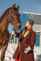 Obraz premium A young beautiful girl poses with a horse, winter outdoor