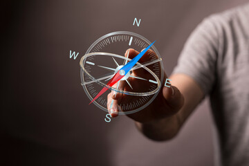 Close-up of a hand holding a digital compass, illustrating direction, guidance, and navigation. Symbolizes decision maki © vegefox.com
