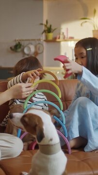 Children playing with colorful toys and pet dog at home in cozy living room. Kids interacting with puppy while learning and developing motor skills through play. Concept of family lifestyle, childhood