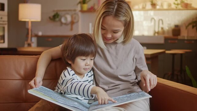 Mother reading book with child and helping with early learning at home. Parent teaching and guiding child through educational activity in family environment. Concept of education, parenting, child