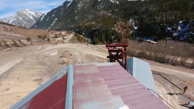 Flying above an old mine with snow capped mountains FPV video Colorado Rockies 4K