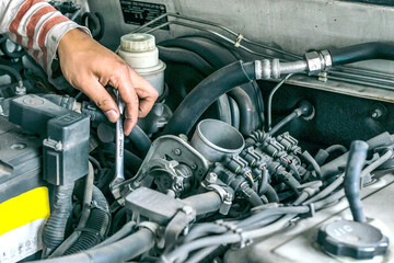 Fototapeta premium closeup hands of Young mechanic checking a car engine in an auto repair shop
