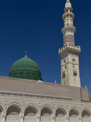 Fototapeta premium Masjid al-Nabawi (the Prophet’s Mosque) in Medina, Saudi Arabia, one of Islam’s holiest sites, featuring its iconic green dome, expansive courtyards, and elegant minarets, visited by millions 