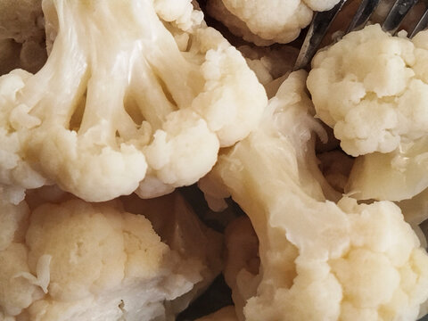 Primer plano de ramilletes de coliflor cocida cubiertos con una salsa cremosa tipo bechamel