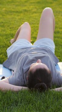 Woman lies on grass dreaming and visualizing future aspirations. Relaxed dreamer finds inspiration in peaceful outdoor setting. Woman contemplates dreams. Inspiring moment and hope. Vertical
