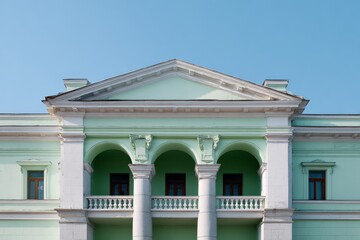 Naklejka premium Mint green neoclassical building front with three arches flanked by columns balustrade and decorative pediment against clear sky