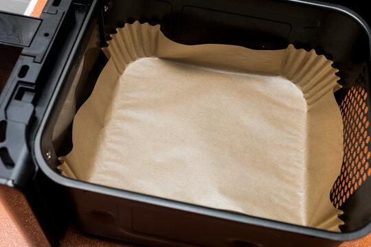 Air fryer basket with parchment paper liner ready for cooking at home