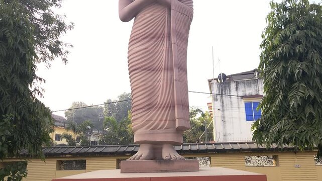 Standing Buddha statue in outdoor setting in India. Symbol of peace, meditation, and spirituality. Buddhist sculpture in temple or public area representing calmness, enlightenment, Bodh Gaya, Bihar.