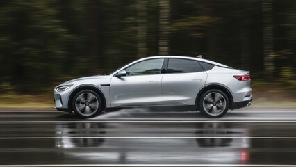 Fototapeta premium Silver coupe SUV speeds on wet road, blurred backdrop of a forest