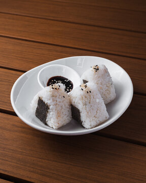 White plate holds three rice balls with seaweed