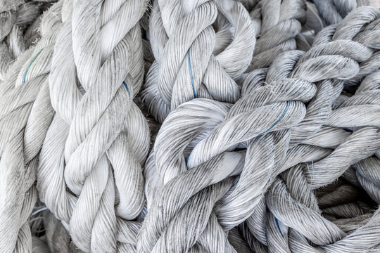Thick braided ropes coiled on wooden dock at harbor pier maritime