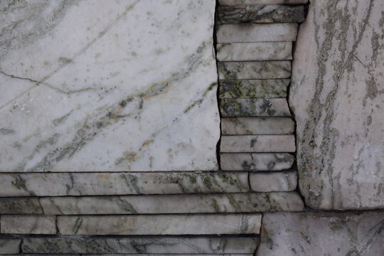 Title: Weathered marble wall with cracks and green veins.
Description: Close view of aged stone showing texture and wear.