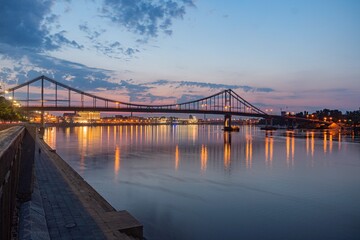 Fototapeta premium Nighttime riverfront scene with illuminated bridge and buildings a