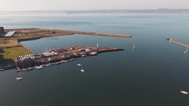 Aerial drone flight over Granton Harbour and marina with yachts towards the Firth of Forth in Edinburgh, Scotland
