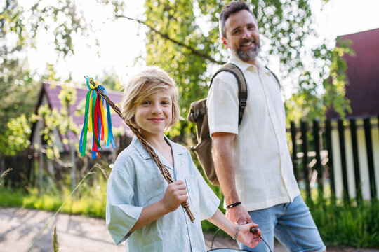Dad and son walking with Easter whip and bucket during Easter Monday visits.