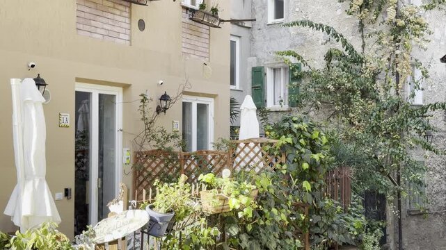 Limone sul Garda, Lake Garda, Italy, Italian village, residential alley, narrow street, old town, white houses, green shutters, snow-capped mountains, alpine backdrop, terracotta roof, Mediterranean v