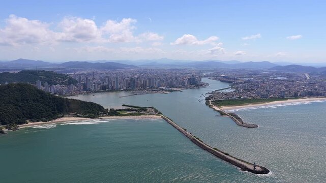 Aerial wide shot of Itajai harbor entrance and river meeting the ocean, highlighting port access and coastal infrastructure.