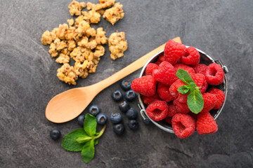 Fresh Raspberries with Mint in Metal Bucket with Blueberries, Granola and Wooden Spoon on Dark Slate — Healthy Berry Food Photography © Jan