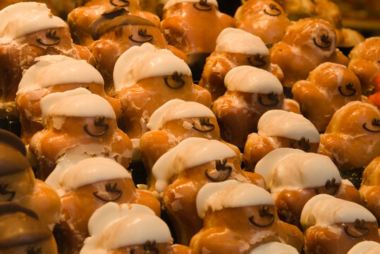 Rows of traditional glazed pastry pigs with smiling faces at a bakery market stall