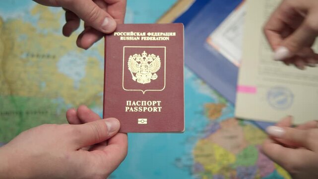 Close up shot shows migration officer handing over new Russian foreign passport with biometric symbol to citizen, while world map and approved stamped documents create official travel and identity
