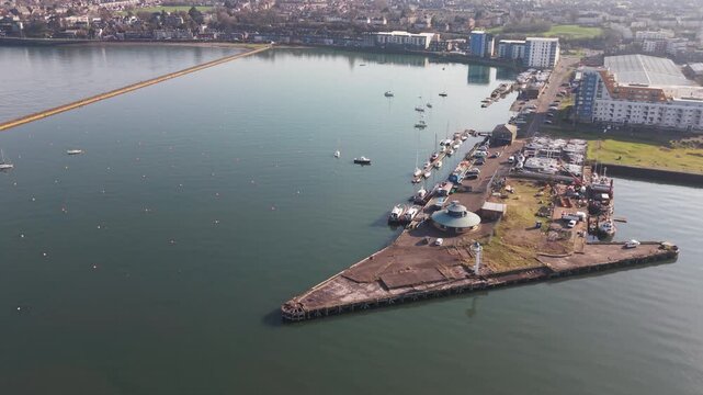 Modern waterfront district with stone breakwaters and sailing yachts at Granton Harbour in Edinburgh, Scotland.