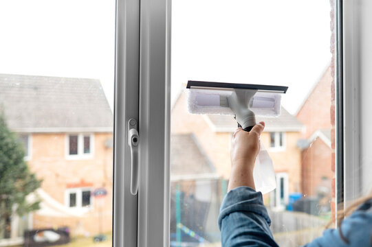 Hand using squeegee to clean window glass indoors, household chore, hygiene care, cleaning routine.