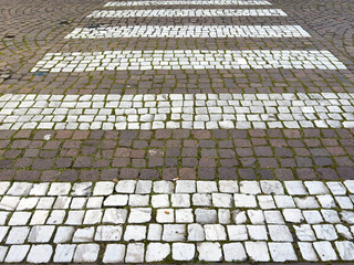 Fototapeta premium Cobblestone crosswalk with white stripes on brick road