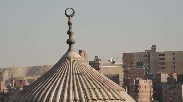 Birds circle above the dome with spire of mausoleum at Islamic cemetery in Cairo Egypt