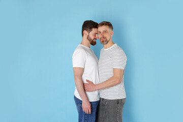 Fototapeta premium Happy gay couple on light blue background