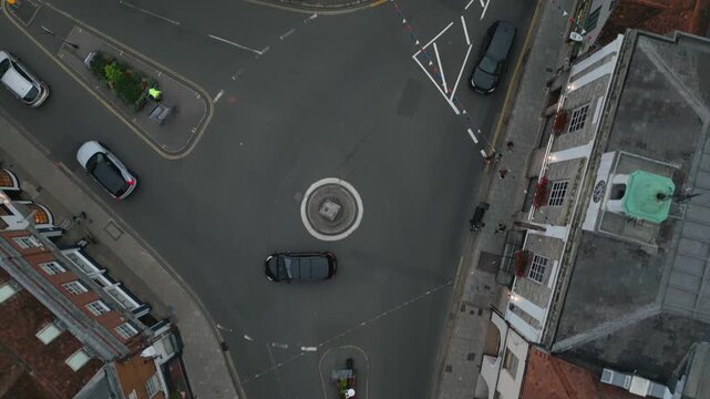 An aerial view of a roundabout with cars, buildings, and street decorations.