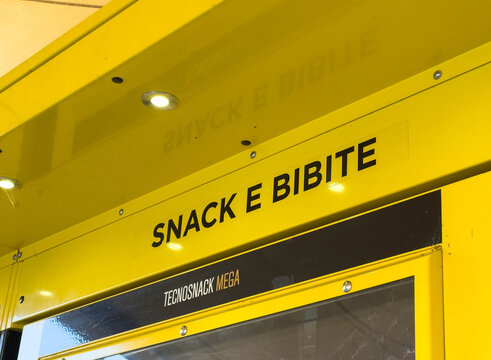 Conegliano, Italy - January 27, 2026: Yellow vending machine labeled "SNACK E BIBITE" with illuminated signage and a sleek modern design in a public space