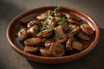 Fototapeta premium Sautéed mushrooms with fresh thyme served on rustic earthenware plate in warm light