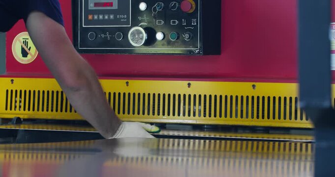 Industrial guillotine shear cutting metal sheet in manufacturing workshop. Blue collar labor and mechanical metal processing at factory
