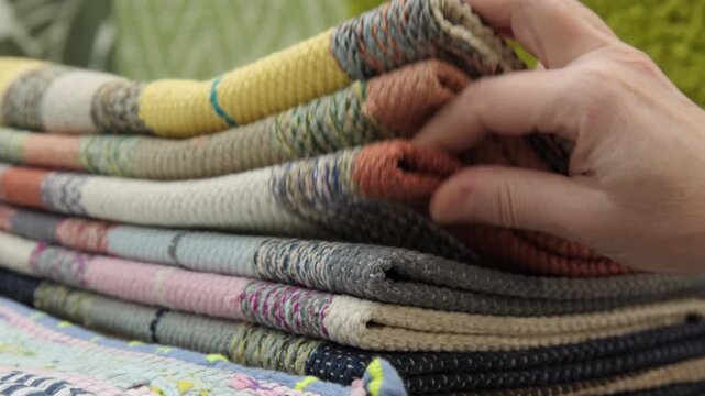 Female hand buyer selects and takes out vintage homespun rug from stack in showroom