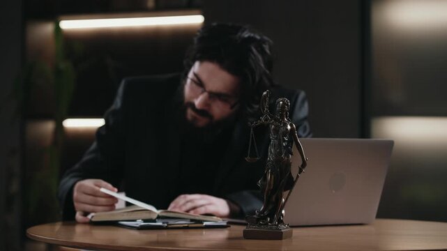 Male lawyer working at office desk with legal documents and Themis statue. Professional legal concept.
