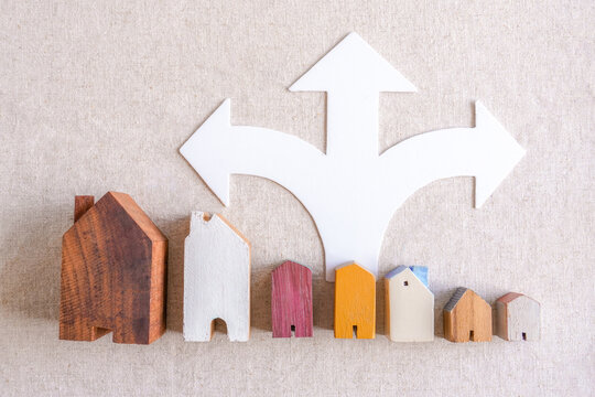 Real estate, house, choice, decision, arrow, direction, home representing property investment options and relocation strategy on a neutral linen background for mortgage planning.