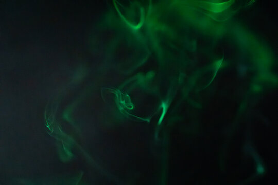 Green smoke swirls gracefully against a dark background creating a mystical atmosphere