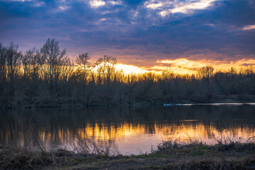 Obraz premium Vistula River near Warsaw at sunset with leafless trees and boat