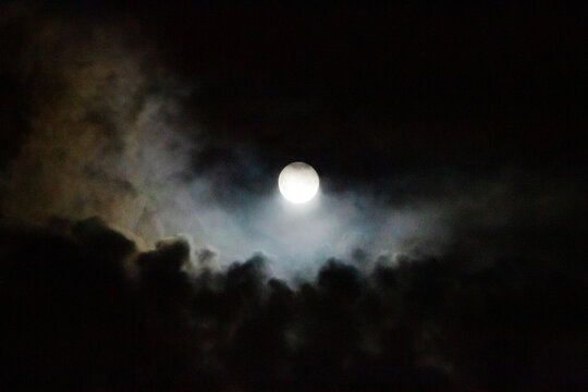Full moon with colorful clouds rising from below